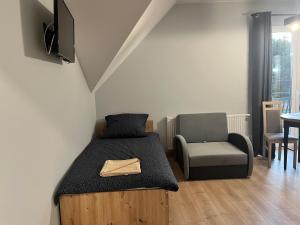 niewielka sypialnia z łóżkiem i krzesłem w obiekcie Apartamenty Na Rozstaju w Kluszkowcach