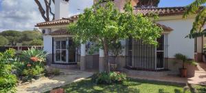 uma casa com um portão e uma árvore no quintal em Beach house near Tennis Club La Barrosa em Chiclana de la Frontera