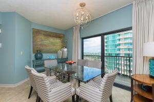 comedor con mesa de cristal, sillas y ventana en The Palms 1001, en Orange Beach