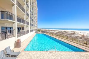 una piscina frente a un edificio con playa en The Palms 1001, en Orange Beach