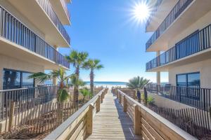 un paseo marítimo que conduce a la playa en un complejo en The Palms 1001, en Orange Beach