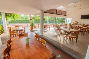 um restaurante vazio com mesas e cadeiras de madeira em GHL Hotel Club el Puente em Girardot