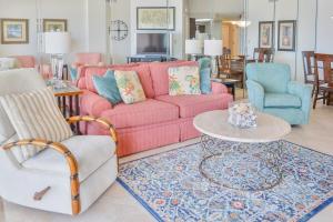 a living room with a pink couch and two chairs at The Palms 314 in Orange Beach