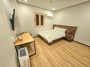 Habitación pequeña con cama y escritorio con ordenador. en Hotel Jeong Ansan Seonbu en Ansan