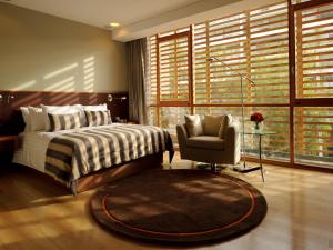 a bedroom with a bed and a chair and a window at NOI Vitacura in Santiago
