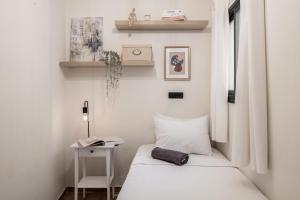 a small white room with a bed and a table at the train studio in Jerusalem