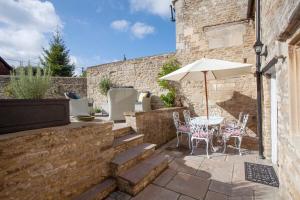 a patio with a table and an umbrella at ※ Charming Country House Nr Bath (WC)※ in Biddlestone