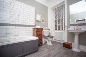 a bathroom with a tub and a toilet and a sink at The Georgian Townhouse @ Pierrepont Place in Bath