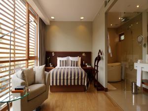 a bedroom with a bed and a couch and a bathroom at NOI Vitacura in Santiago