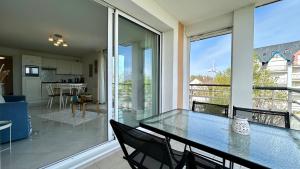 a dining room with a glass table and a balcony at Pointe de Sel, appartement face au port du Crotoy in Le Crotoy