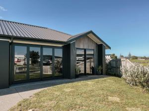 una casa con ventanas de cristal y techo en Retro Style Beach Retreat - Matarangi Holiday Unit, en Matarangi