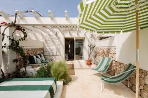 a patio with green and white umbrellas and chairs at Morvedra Nou Luxury Boutique Hotel - Adults Only in Ciutadella