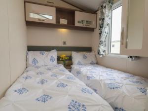 two beds in a small room with blue and white sheets at 47 The Drake Forgetmeknot in Scarborough