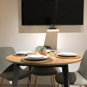 a wooden table with chairs and plates and a television at Eden Condo Athens in Athens