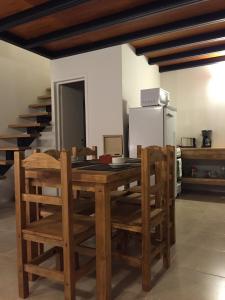 cocina con mesa de madera con sillas y nevera en Ukurj Apartamentos en Ushuaia