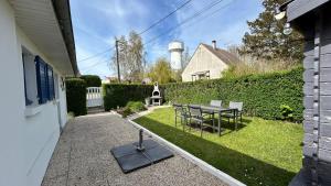 a backyard with a table and chairs and a lighthouse at Les Alouettes, maison avec studio pour 4 personnes proche de la baie. in Le Crotoy