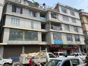 a building on a busy city street with cars at Aizawl Homestay in Āīzawl