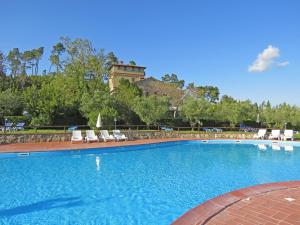 a swimming pool with chairs and a building in the background at Il Doccino in Riparbella