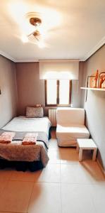 Precioso apartamento renovado en Avilés في أفيليس: غرفة صغيرة بها سريرين وأريكة