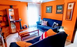 a living room with blue couches and an orange wall at Precioso apartamento renovado en Avilés in Avilés