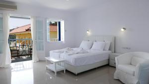 マラトカンボスにあるLimnionas Bay Village Hotelの白いベッドルーム(白いベッド1台、椅子付)