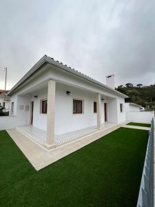 Biały dom z zielonym trawnikiem przed nim w obiekcie Casa Santa Rita w mieście Alcobaça