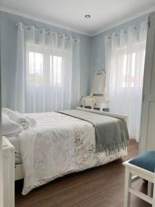 a white bedroom with a bed and a mirror at Casa Santa Rita in Alcobaça