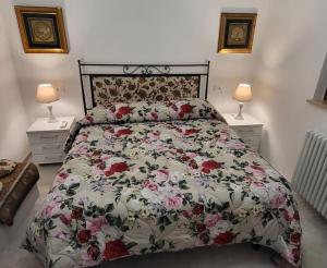 a bedroom with a bed with a floral comforter and two lamps at Sweet Home Offida in San Giovanni in Strada