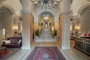 a lobby with a staircase and a chandelier at Grand Hotel di Parma in Parma
