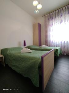 a bedroom with two beds with green sheets and a window at Casa Aris Fiera Vicenza in Vicenza
