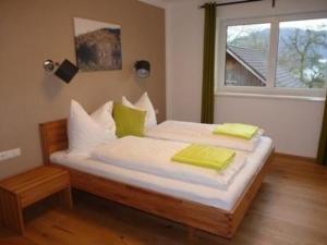 een slaapkamer met een bed met witte lakens en groene kussens bij Appartement in Altmünster Am Traunsee mit Panoramablick in Altmünster
