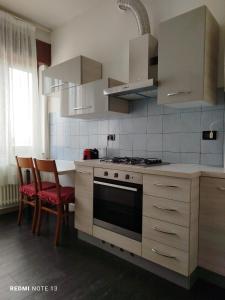 cocina con armarios blancos, fogones y sillas en Casa Aris Fiera Vicenza, en Vicenza