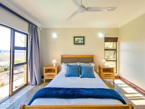 ein Schlafzimmer mit einem großen Bett mit blauen Kissen in der Unterkunft Shiloh Cottage in Champagne Valley