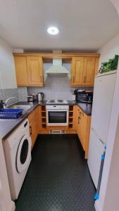 a kitchen with wooden cabinets and a washer and dryer at No.62 Fivedom - Luxury apartment in Southampton