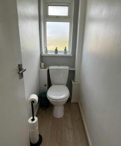 a small bathroom with a toilet and a window at Contractors welcome 3 bed house with parking by Eagle Owl Stays in Crawley