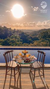 una mesa con comida y bebida en la parte superior de un balcón en Pousada Recanto Sol Nascente, luxo e proximidade com a natureza en Rio Formoso