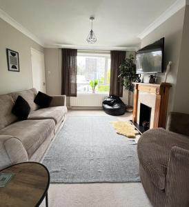 a living room with a couch and a fireplace at Contractors welcome 3 bed house with parking by Eagle Owl Stays in Crawley