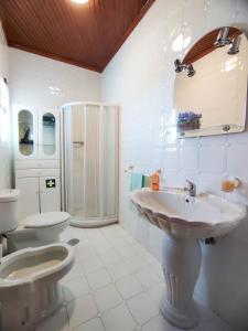 a white bathroom with a sink and a toilet at Vila Almeida in Ponta Delgada