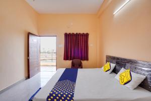 ein Schlafzimmer mit einem Bett, einem Stuhl und einem Fenster in der Unterkunft SPOT ON Hotel Pragya 5 in Raipur