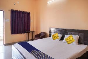 Schlafzimmer mit einem Bett mit gelben und blauen Kissen in der Unterkunft SPOT ON Hotel Pragya 5 in Raipur