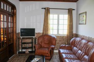 a living room with a leather couch and a television at Vila Almeida in Ponta Delgada