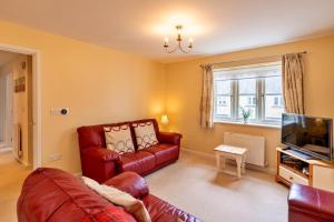 a living room with a red leather couch and a television at Finest Retreats - Hardie Close in Tetbury