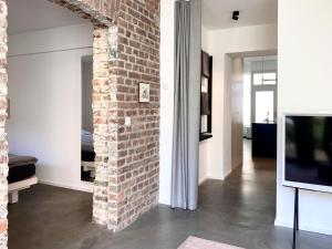 ein Wohnzimmer mit einer Ziegelwand und einem TV in der Unterkunft Zehuus Gartenstudio mit Terrasse in Köln