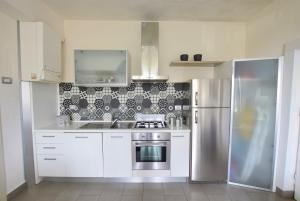 a kitchen with white cabinets and a stainless steel refrigerator at Marco' s apartment in San Vincenzo