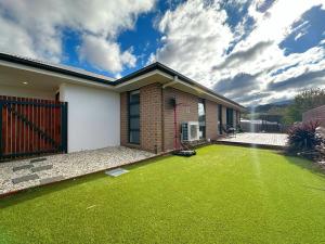 a house with a yard with green grass at New Kingston Trampoline House in Kingston