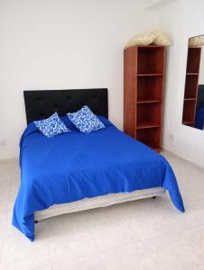 Una cama azul con dos almohadas encima. en Departamentos el Peregrino en San Luis