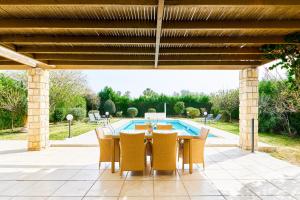 eine Terrasse mit Tisch und Stühlen und einem Pool in der Unterkunft Villa Anassa Privat Pool Near Beach in Klorakas