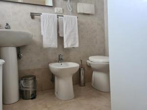 a bathroom with a sink and a toilet and towels at Lido Venere Case Vacanze in Metaponto