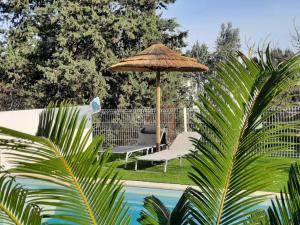 ein Tisch und zwei Stühle unter einem Sonnenschirm neben einem Pool in der Unterkunft Villa climatisée piscine in Montpellier