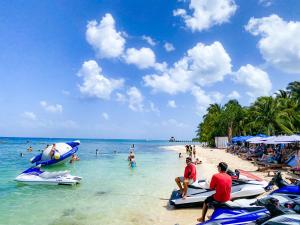 a group of people on a beach with people in the water at Maia Suites Cozumel in Cozumel